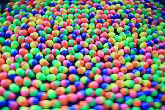 Colorful rainbow of small round candy balls scattered on a flat surface, showcasing vibrant colors, ideal for food, sweets, and fun-themed photography. photo