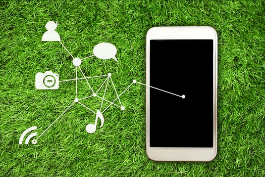Smartphone on vibrant green grass background with connected media and social network icons, representing technology, communication, and modern digital lifestyle concepts. photo
