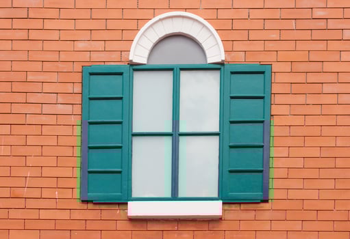 Bright green wooden window shutters on orange brick wall with white arched frame, European style architecture exterior, perfect for travel, building, and design themes. photo