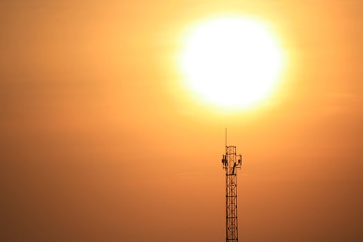 A cell tower with the sun behind it photo
