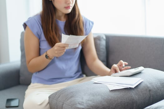 Asian woman holding paper document calculating money savings paying bills in mobile application using smart phone payment online with paying household bills tax insurance managing budget. photo