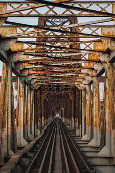 Old rusty iron traditional railway Long Bien bridge structure over the road in Hanoi city photo