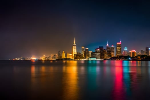 the city skyline at night with lights reflecting off the water. AI-Generated photo