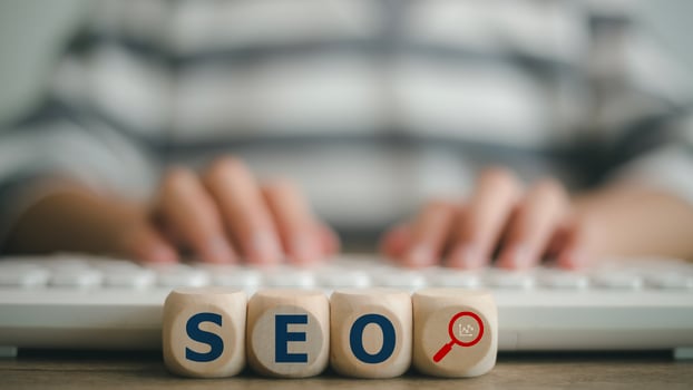 Search Engine Optimization SEO concept on wooden cubes with a woman using a computer keyboard. photo