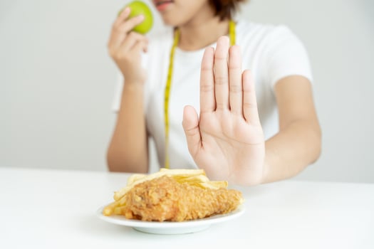 slim female body confuse French fries and fried chicken. Woman in restaurant achieves weight loss goal for healthy life, crazy about thinness, thin waist, nutritionist. Diet, body shape. photo