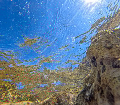 Underwater image of a rocky coastline with turquoise water towards the surface photo