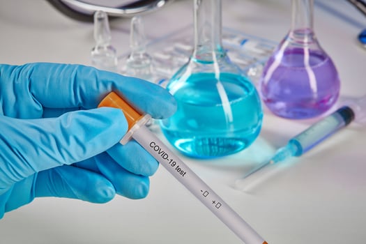 Hands in blue gloves holding Coronavirus testing kit. Medical flasks, colorful chemical reagents. Ampoules, syringe, phonendoscope isolated on white photo