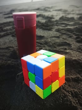 Rubik and coffee tumbler on the sand by the sea photo