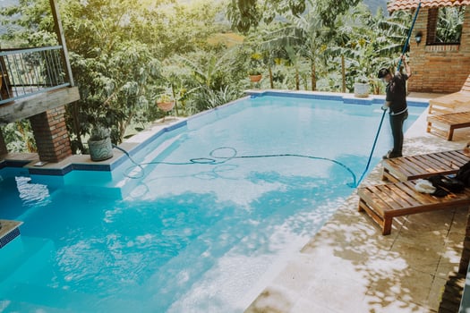 Pool maintenance and cleaning with vacuum suction hose. Worker cleaning a beautiful swimming pool with vacuum suction hose photo