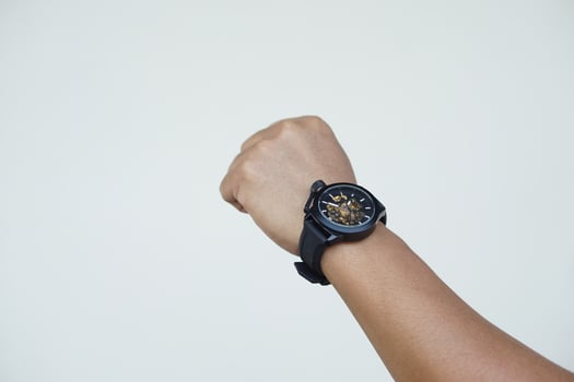 Close up man hand wears black watch againts gray wall background. Concept, fashionable accessory for time telling, make you look stylish, punctual and smart. Analog wrist watch. photo