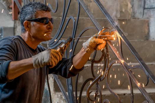 Man wearing protective glasses welds metal with welding machine in a private house. Interior welding work. Closeup. photo