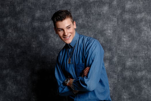 Man in denim shirt, arms on hips, gray background. photo