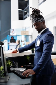 Showroom stylish employee standing at cash register, preparing clients packages. African american worker putting fashionable clothes in cardboard boxes, working in shopping centre. Fashion concept photo