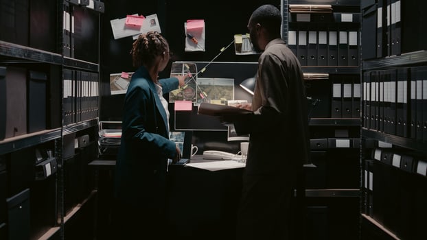 African american officers talking about evidence in office, looking at case files to find suspect. Team of investigators reading statements in police archive space, doing background checks. photo