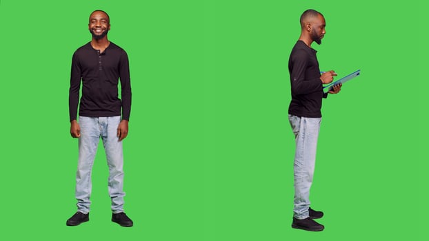 Confident man posing on camera and taking notes, writing important information using pen and clipboard papers. Casual male model standing over greenscreen bacground, leisure activity. photo
