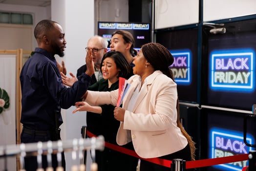 Anxious diverse people wait in line for discounts and deals, standing in behind red tape at clothes shop entrance waiting for opening. Shoppers ready to start Black Friday shopping photo