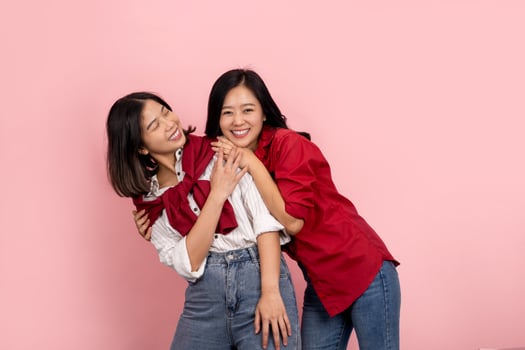 Happy Asian lesbian couple standing on pink background photo