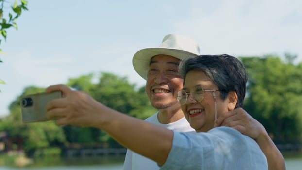 Happy and healthy couples Asian photo and VLOG selfie together for social media in park on leisure. Family and friendship lifestyle, Enjoyment of active seniors, and outdoor activity after retirement