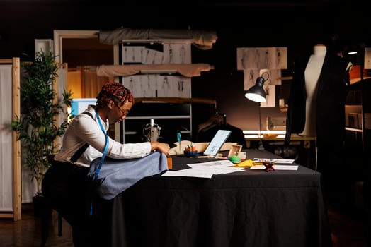 African american seamstress using industrial sew machine to do creative embroidery on piece of fabric to be used on upcoming bespoke fashion collection. Expert tailor working on sartorial collection photo