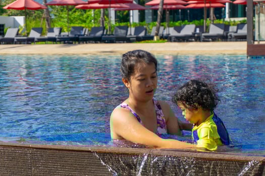 Asian child boy learn swimming in a swimming pool with mom photo