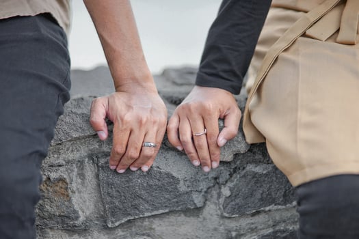 a couple holding hands on a rock wall photo