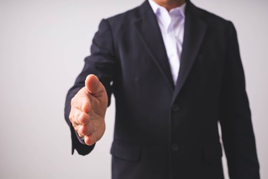 A businessman in a black suit stands and raises his hands. photo