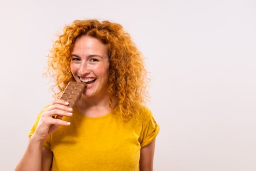Portrait of happy cute ginger woman enjoys eating chocolate photo