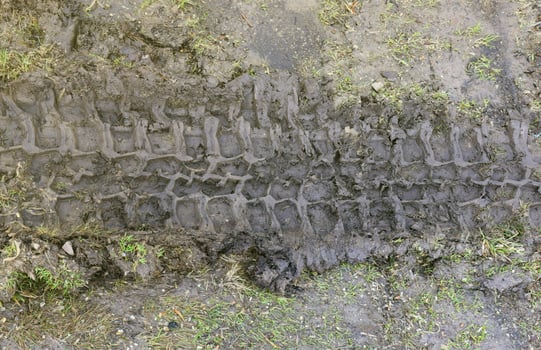 Wheel track on mud. Traces of a tractor or heavy off-road car on brown mud in wet meadow photo