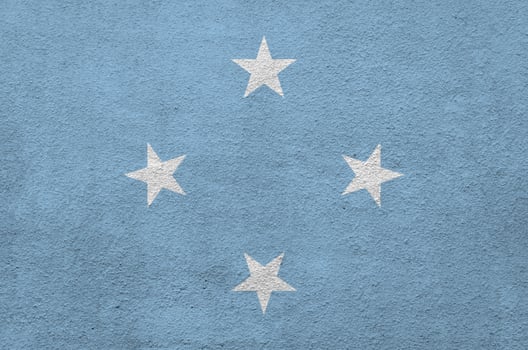 Micronesia flag depicted in bright paint colors on old relief plastering wall. Textured banner on rough background photo