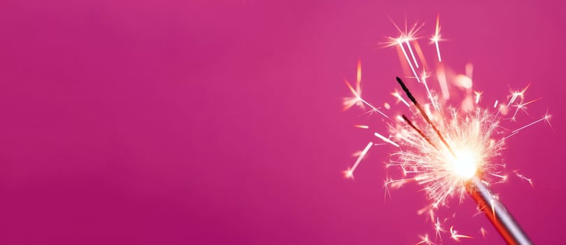 Bright burning sparkler stick on pink background banner. Generate ai photo
