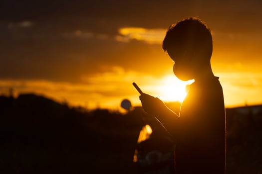 Asian boy using smartphone at sunset photo