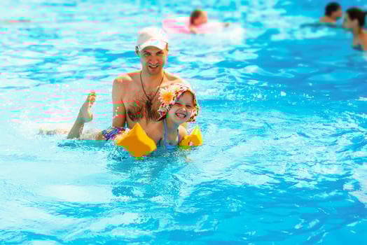 Father playing with his daughter in swimming pool photo
