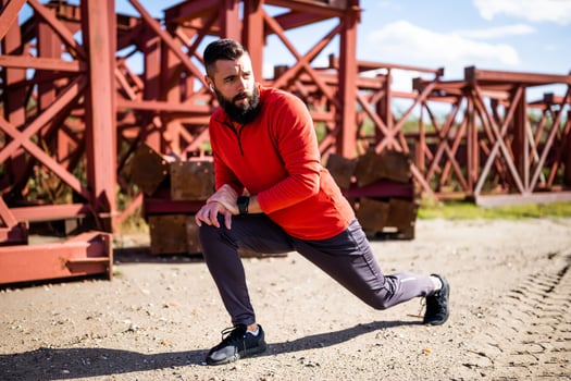 Adult man is exercising outdoor on sunny day. He is stretching his body. photo