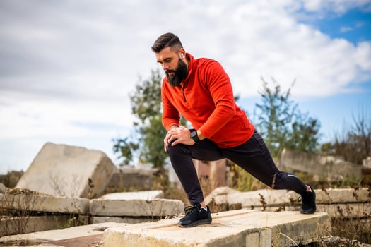 Adult man is exercising outdoor on sunny day. He is stretching his body. photo