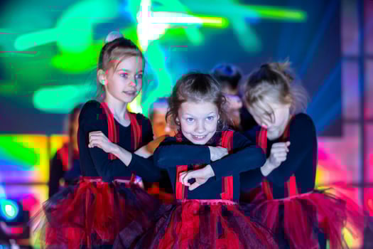 Little girls are performing a dance number. Dance for Helovinna in red suits. Girl dancing. Emotional performance of a children's dance group. photo