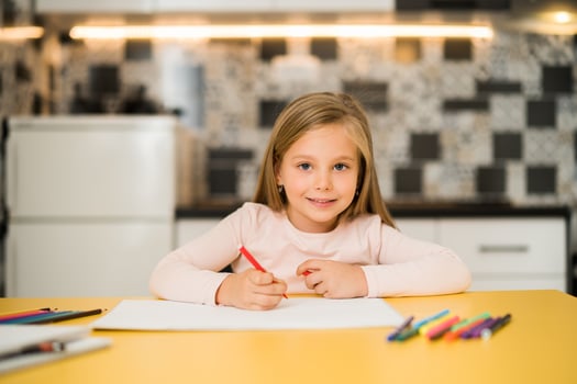 Beautiful little girl enjoys drawing at her home photo