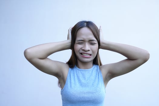 Asian woman covers her ears with her hands to prevent hearing photo
