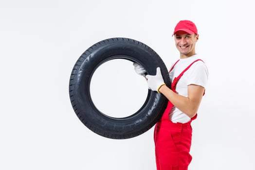 Mechanic carrying a tyre on a white background photo