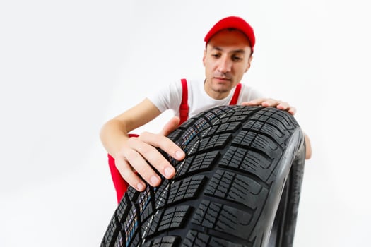 Closeup of mechanic hands pushing a black tire in the workshop. photo