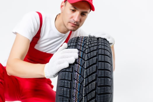 Mechanic Holding Car Tire on a white background photo