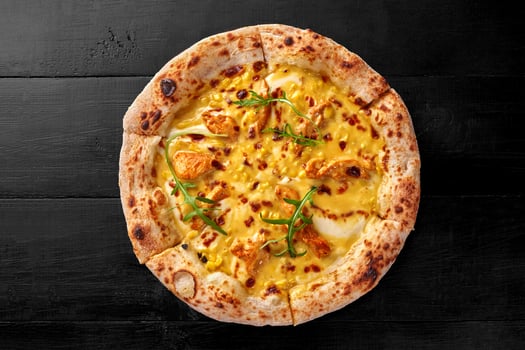 Pizza with cream cheese sauce, chicken fillet, corn, mozzarella and cheddar on black wooden surface photo