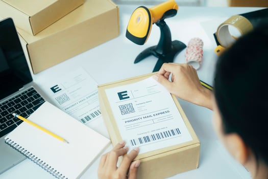 Young business owner putting shipping label on parcel. photo
