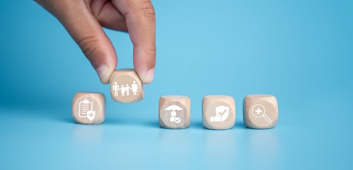 Health insurance and healthcare concept, human hand holds wooden block with icons about health insurance and healthcare access, retirement planning on blue background. photo
