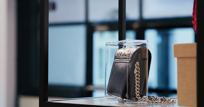 Selective focus of trendy black bag in empty modern boutique, filled with multiple racks with fashionable clothes and trendy accessories. Shopping mall equipped with stylish merchandise photo