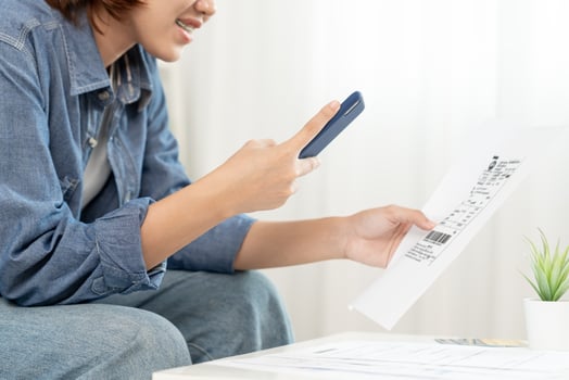 Young woman use phone to scan barcode or QR codes to pay credit card bill after receiving document invoice online. payment, receive, paying electricity, digital payments, technology, scanning photo