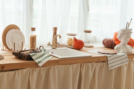 Kitchen countertop by the window in a bright room. Orange pumpkins, bread and pasta on the countertop. Autumn mood at home. photo