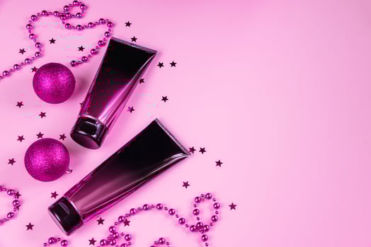 Set of black and pink squeeze cosmetic bottles and Christmas decorations on pastel background. photo