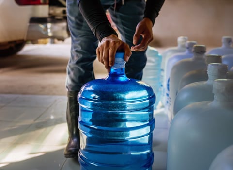 Workers lift drinking water clear and clean in blue plastic gallon into the back of a transport truck purified drinking water inside the production line to prepare for sale.small business photo