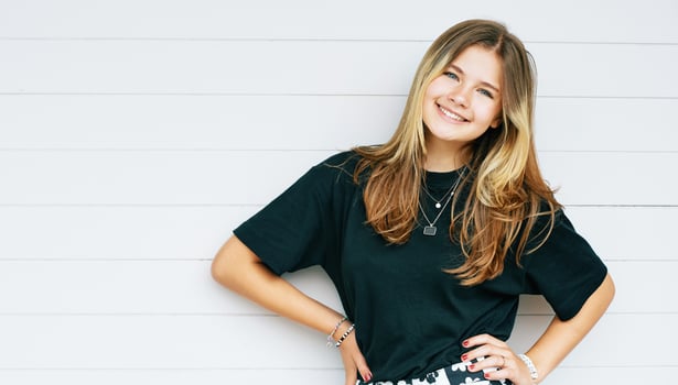 Outdoor portrait of pretty young teenage gir with brown hair posing on white background, wearing black t-shirt photo