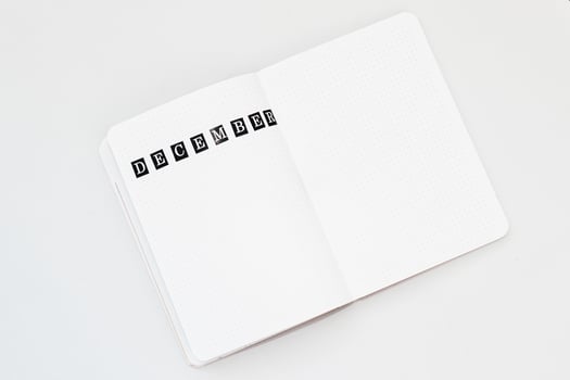 Filling in the diary, writing December in a notebook in a dot photo